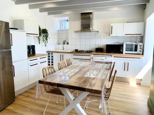 une cuisine avec une table en bois et des armoires blanches dans l'établissement La Maison Bleue, à Pleumeur-Bodou