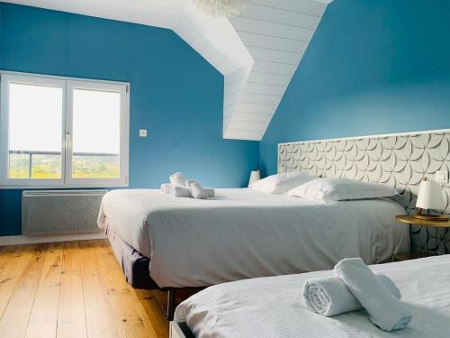 - une chambre bleue avec 2 lits et une fenêtre dans l'établissement La Maison Bleue, à Pleumeur-Bodou