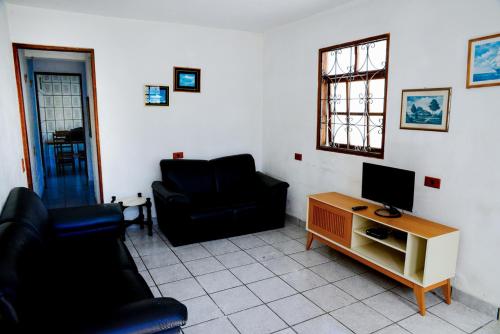 a living room with two black chairs and a television at Casa com otima localizacao e churrasqueira in Ilhabela