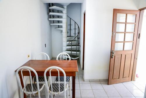 a dining room with a wooden table and white chairs at Casa com otima localizacao e churrasqueira in Ilhabela