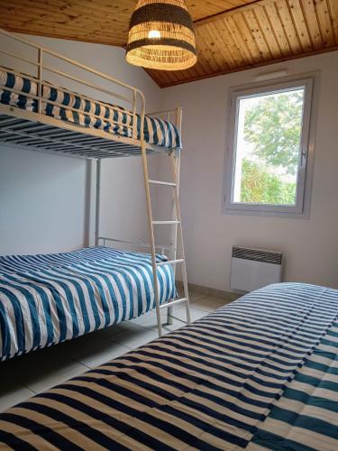 une chambre avec deux lits superposés et une fenêtre dans l'établissement Maison familiale à 600m de la plage 8mn à pieds, à Saint-Vincent-sur-Jard