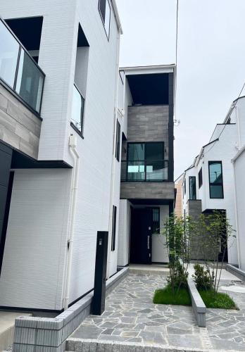 a white house with a black door and a courtyard at A newly built house a 4 minute walk from the station, Free parking & Let's enjoy the night view together! in Tokyo