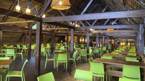an empty restaurant with green chairs and tables at Hotel Amazon by On Vacation in Leticia