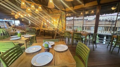 a restaurant with wooden tables and green chairs at Hotel Amazon by On Vacation in Leticia