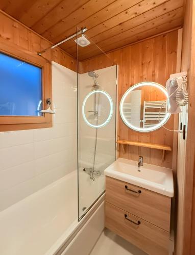a bathroom with a shower and a sink and a mirror at Chalet Des Charmes in Thollon