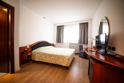 a bedroom with a bed and a desk and a television at Hotel Donizetti in Lallio
