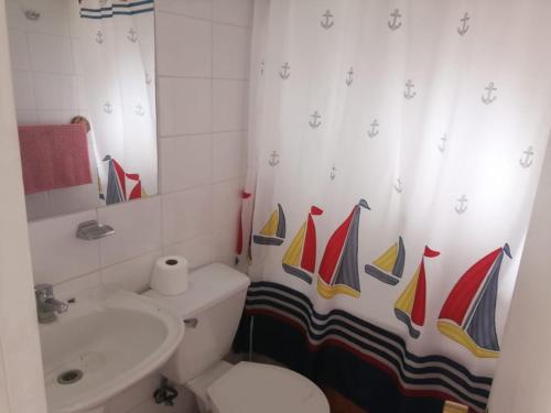 a bathroom with a toilet and a sink with a sail shower curtain at House in Maitencillo Norte, 5 minutes from the beach in Puchuncaví