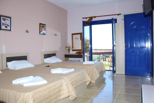 two beds in a room with a blue door at Michelle's Studios in Anaxos