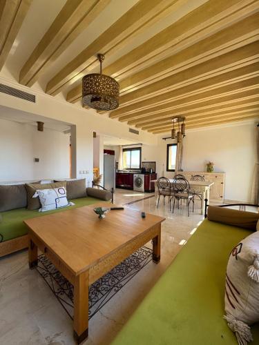 a living room with a table and a couch at Cosy Appartement Avec Piscine, Terrain tennis et loisirs in Marrakech