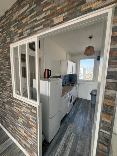 - une cuisine avec des appareils blancs et un mur en briques dans l'établissement Fort de Tourneville Le Tétris, au Havre