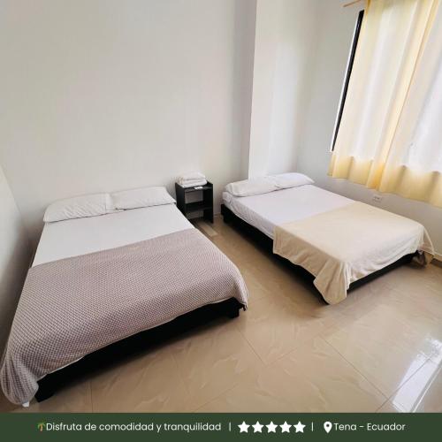 two beds in a small room with a window at RinaKawsay - ViveViajando Apartamento amoblado en Tena in Tena