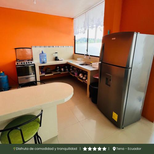 a kitchen with a black refrigerator and a table at RinaKawsay - ViveViajando Apartamento amoblado en Tena in Tena