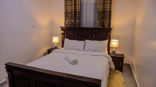 a bedroom with a large bed with two lamps at KYM'S Superstays in Meru