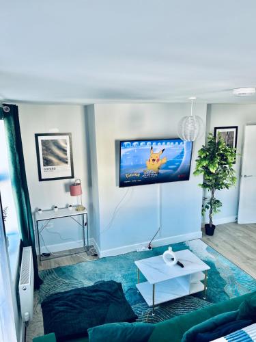 a living room with a couch and a tv on the wall at Folkestone Harbour Modern Comfortable Flat in Folkestone