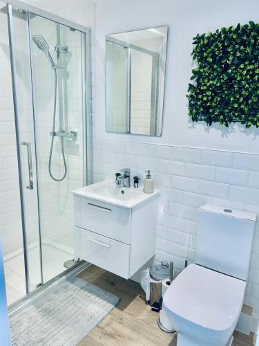 a white bathroom with a shower and a toilet at Folkestone Harbour Modern Comfortable Flat F3 in Folkestone