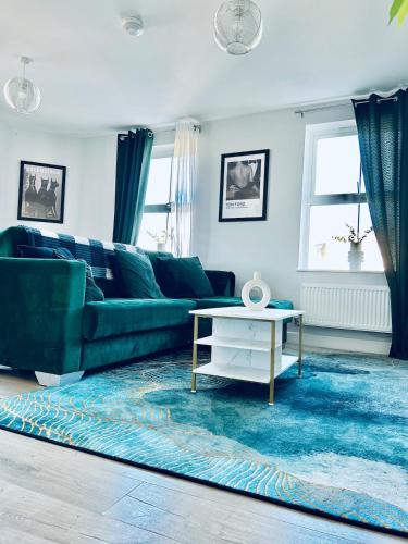 a living room with a green couch and a table at Folkestone Harbour Modern Comfortable Flat in Folkestone
