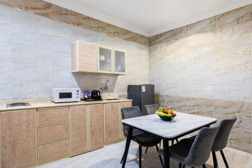 a kitchen with a table with chairs and a microwave at The Palace Hotel Suites - Al Badea in Abha