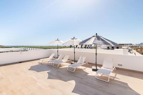 a group of white chairs and umbrellas on a roof at Casa Cabo - THE BEST, fully equipped luxurious brand new condo in Cabo San Lucas