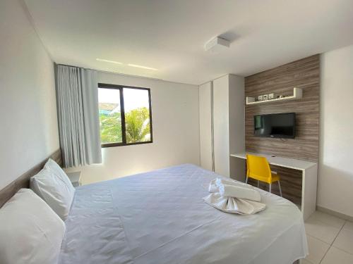 a bedroom with a white bed and a yellow chair at Carneiros Beach Resort in Praia dos Carneiros