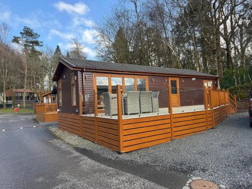 a large wooden cabin with a deck with chairs at Lakeview Lodge Whitecross bay in Troutbeck Bridge