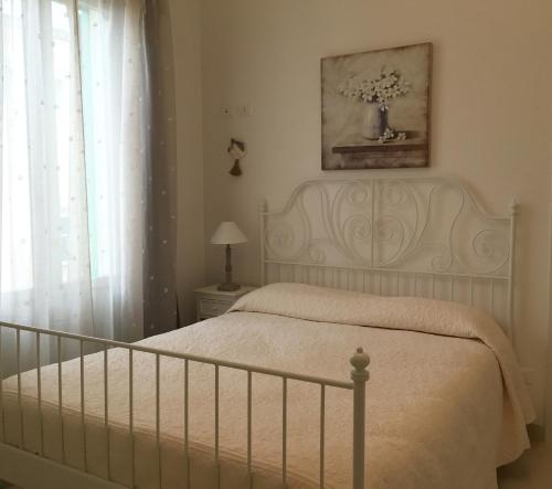 un letto bianco in una camera da letto con un vaso sul muro di Dimora Del Sorriso a Monopoli