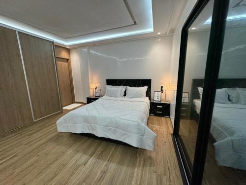 a bedroom with a large white bed and a mirror at Lusail in Beni Mellal