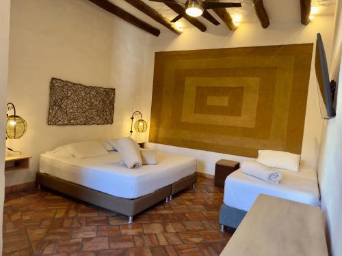 a bedroom with two beds and a painting on the wall at Hotel Boutique Casa Encanto Barichara in Barichara