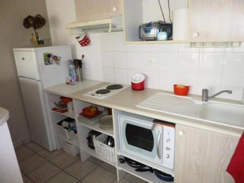 une petite cuisine avec un évier et un micro-ondes dans l'établissement Résidence Argos - Location de Vacances - PORNICHET - 2 pièces - 021 - 60409 MAE-7411, à Pornichet