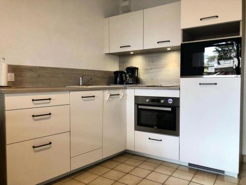 une cuisine avec des armoires blanches et un four dans l'établissement Résidence La Yole - PORNICHET T3 PROCHE PLACE DU MARCHE MAE-7401, à Pornichet