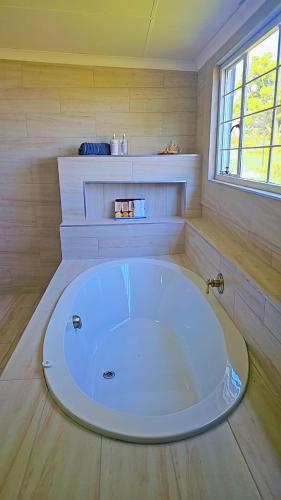 a large white tub in a room with a window at CenoeN Country Suites in Rooipoort