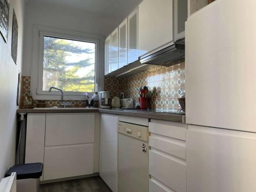 Elle comprend une petite cuisine avec des placards blancs et une fenêtre. dans l'établissement Résidence Le Concorde - PORNICHET - APPARTEMENT VUE MER PROCHE QUARTIER GARE MAE-7461, à Pornichet