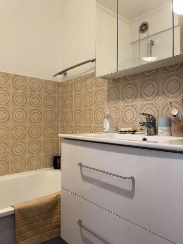 La salle de bains est pourvue d'une baignoire, d'un lavabo et d'une armoire blanche. dans l'établissement Résidence Le Concorde - PORNICHET - APPARTEMENT VUE MER PROCHE QUARTIER GARE MAE-7461, à Pornichet