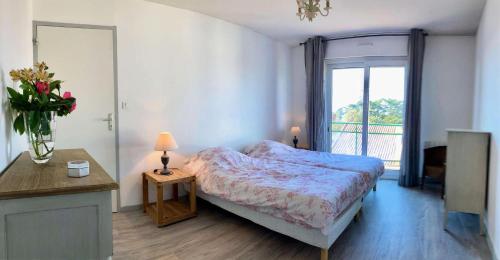 - une chambre avec un lit et un vase de fleurs dans l'établissement Résidence Le Brahms - PORNICHET - PROCHE PLAGE ET COMMERCES MAE-7521, à Pornichet