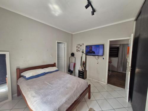 a bedroom with a bed and a tv on the wall at Loft de Quarto e Sala em Vila in Belém
