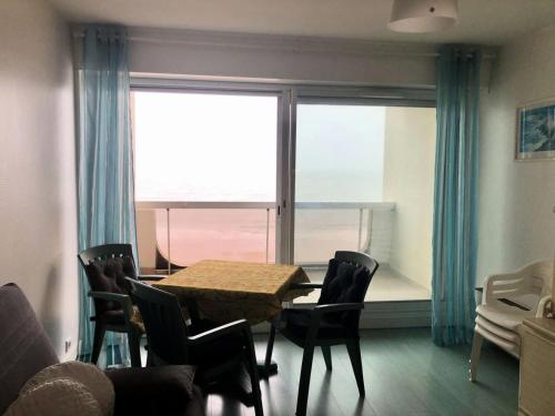 une salle à manger avec une table et des chaises et une fenêtre dans l'établissement Résidence Le Clipper B - La Baule - Appartement Face Mer MAE-2451, à La Baule-les-Pins