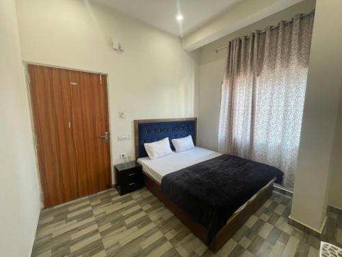 a bedroom with a bed and a wooden door at SAI GUEST HOUSE BANARAS RAILWAY STATION 2km from KASHI VISHWANATH in Varanasi