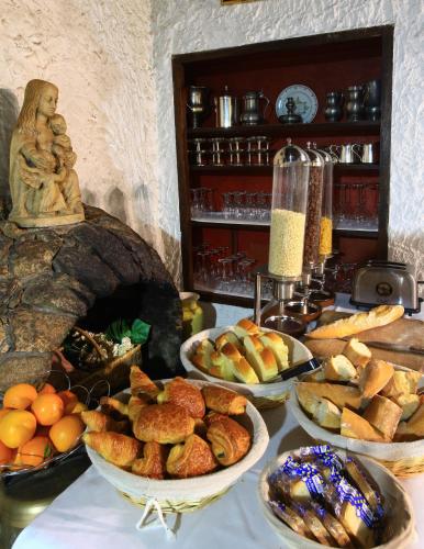 Logis Hôtel La Chaumière في سا لوران سور سيفر: طاولة مليئة بأوعية الخبز والأطعمة الأخرى