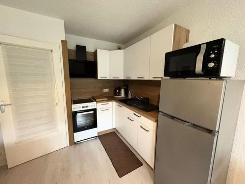 une cuisine avec des armoires blanches et un réfrigérateur en acier inoxydable dans l'établissement Résidence Le Gyserol - PORNICHET - Appartement 2 pièces à 200m de la plage pour 5 personnes MAE-0671, à Pornichet