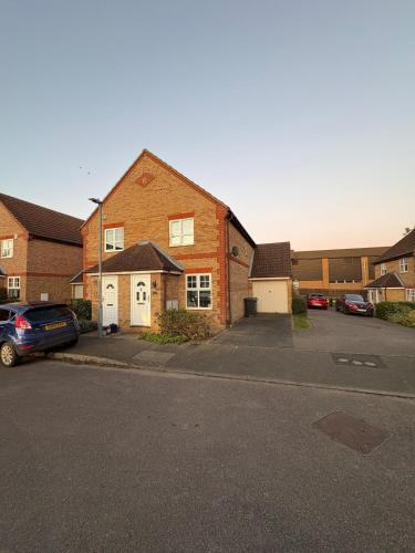 a brick house with a car parked in a parking lot at Northampton 2 King Bed SKY TV Driveway Earls Barton in Earls Barton