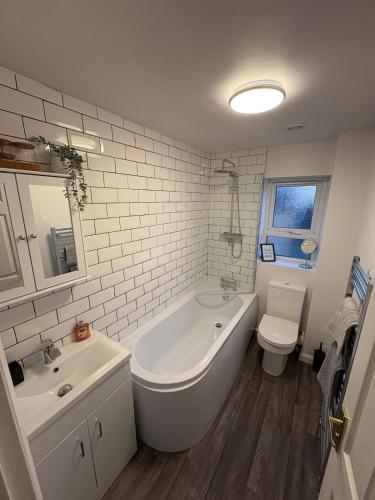 a bathroom with a tub and a toilet and a sink at Northampton 2 King Bed SKY TV Driveway Earls Barton in Earls Barton
