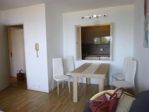 une salle à manger avec une table et des chaises blanches dans l'établissement Résidence Britania - Location de Vacances - LA BAULE - T2 FACE MER - IMMEUBLES EN VAGUES MAE-2901, à La Baule-les-Pins