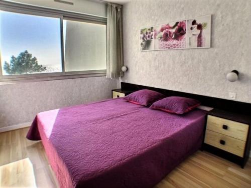 une chambre avec un lit violet et une fenêtre dans l'établissement Résidence Britania - Location de Vacances - LA BAULE - T2 FACE MER - IMMEUBLES EN VAGUES MAE-2901, à La Baule-les-Pins