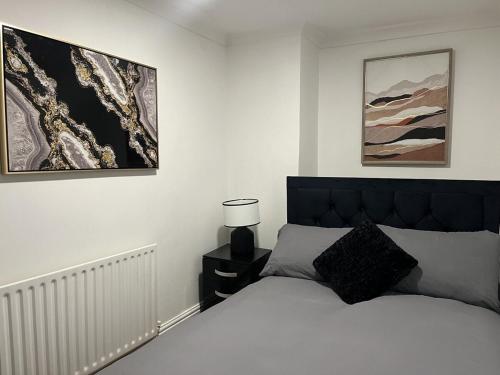 a bedroom with a bed with a black headboard and paintings at Stylish Two Bedroom Apartment in Cardiff