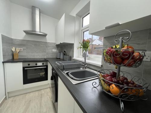 a kitchen with a sink and a bowl of fruit on the counter at Stylish Two Bedroom Apartment in Cardiff