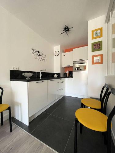 une cuisine avec des armoires blanches et des chaises jaunes dans l'établissement Résidence Les Ibis - PORNICHET CENTRE GARE MAE-2951, à Pornichet