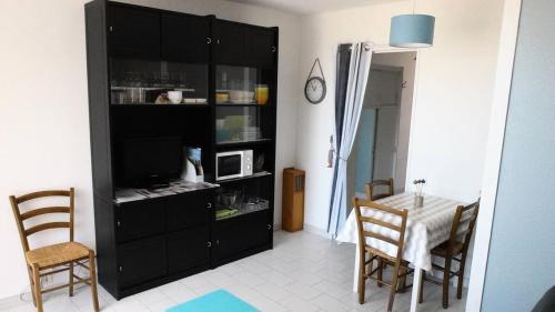 une salle à manger avec une table et une armoire noire dans l'établissement Résidence Les Marines - PORNICHET APPARTEMENT FACE MER MAE-9681, à Pornichet