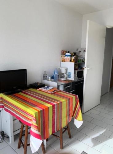 - une cuisine avec une table et une couverture colorée dans l'établissement Résidence Les Marines - Location de Vacances - PORNICHET -T2 FACE MER OCEANES MAE-2921, à Pornichet