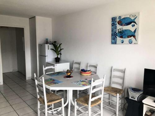 une salle à manger avec une table et des chaises blanches dans l'établissement Résidence Le Trimaran - Location de Vacances - PORNICHET - APPARTEMENT QUARTIER BONNE SOURCE MAE-2931, à Pornichet