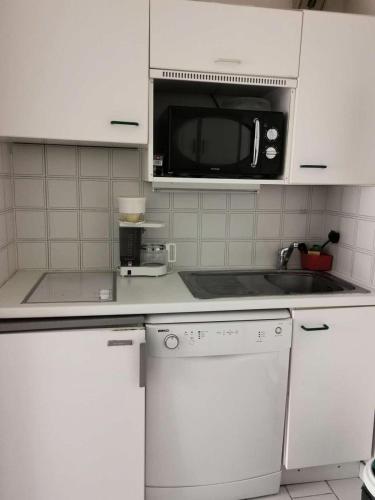 une cuisine avec des armoires blanches et un micro-ondes dans l'établissement Résidence Les Marines - Location de Vacances - PORNICHET - Quartier des Océanes MAE-9691, à Pornichet