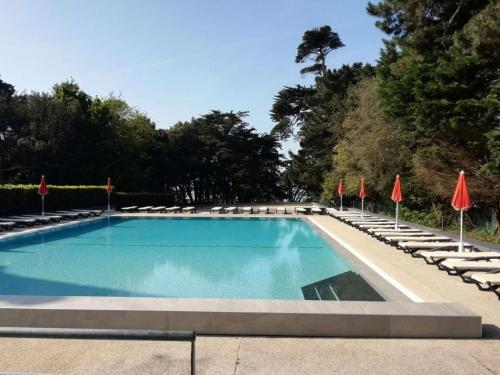une grande piscine avec chaises longues et parasols dans l'établissement Résidence Ker Juliette - Pornichet - Résidence Ker Juliette MAE-9721, à Pornichet